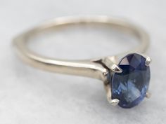 This is a well-proportioned ring, classic and sophisticated. The brightly polished sides have a great heft to them, and this is comfortable on the finger, with a rich feel. We've set the center with a bright blue Ceylon sapphire that has glittering navy and cobalt highlights and plenty of sparkles.Metal: 14K White GoldGem: Sapphire 1.85 CaratsGem Measurements: 6.2 x 8.6 mm, OvalAccents: Diamond .01 Carats, J in Color, I in ClarityRing Size: 9Marks: "14Kt" Stamped on the inside band Classic Oval Sapphire Ring, Timeless Sapphire Promise Ring With Round Band, Classic Sapphire Ring In 14k White Gold, Classic Sapphire Birthstone Ring, Timeless Sapphire Promise Ring, Classic Sapphire Halo Ring, Classic Oval Sapphire Ring With Polished Finish, Classic Blue Sapphire Diamond Ring, Modern Round Sapphire Ring For Formal Occasions