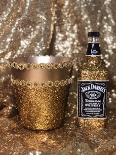 a bottle of jack daniels whiskey sitting next to a cup filled with gold flakes