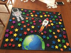 a wooden table topped with stars and a space ship on top of the floor next to a phone