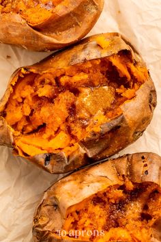 three baked sweet potatoes sitting on top of a piece of parchment paper with the tops peeled off