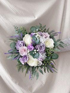 a bridal bouquet with purple and white flowers on a draped fabric background for a wedding or special event