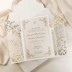 a white and gold wedding card on top of a table