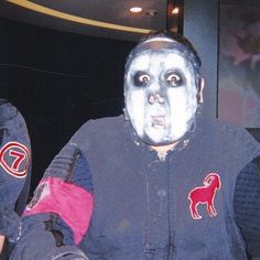 two people with painted faces and face paint on their bodies, one is wearing a baseball jacket