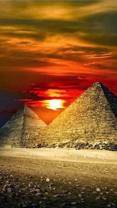 two pyramids in the desert at sunset