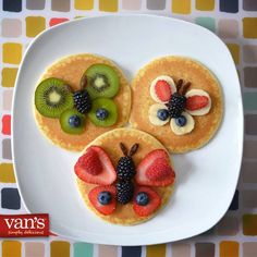 a plate topped with pancakes covered in fruit and veggies next to cupcakes