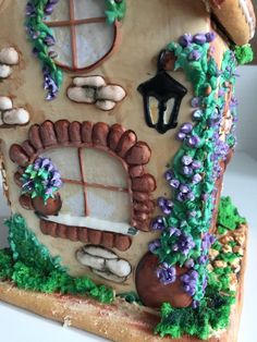 there is a cake that looks like a house with windows and flowers on the outside