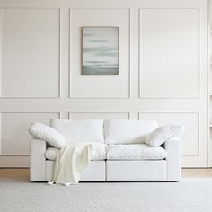 a white couch with a blanket on it in front of a wall that has paneled panels