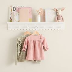 a baby's clothes hanging on a shelf next to a stuffed animal and other items