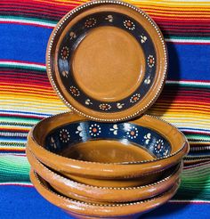 three wooden bowls sitting on top of a colorful cloth covered tablecloth next to each other