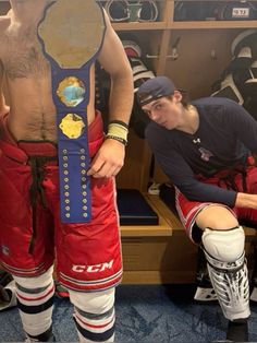 a man in red and white pants standing next to a mannequin with a blue belt around his waist