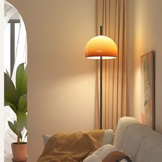 a bedroom with a bed, lamp and potted plant on the side of the bed