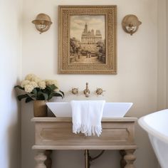 a bathroom sink sitting under a painting on the wall