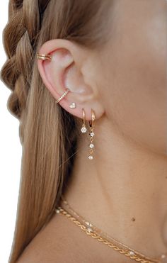 a close up of a woman's ear wearing gold earrings and chain bracelets