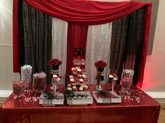 a red table topped with lots of cupcakes and desserts on top of it