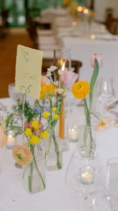 flowers in vases are on the table at a wedding reception with candles and cards