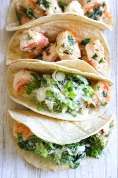 four shrimp tacos are stacked on top of each other