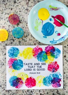 a paper plate that has some paint on it next to a painting with the words taste and see