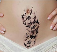 a pregnant woman's stomach with flowers on the side and behind her belly tattoo