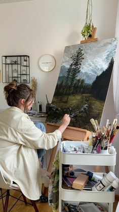 a woman sitting in front of an easel painting