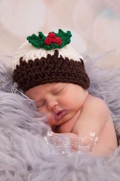 a newborn baby wearing a knitted hat with holly leaves