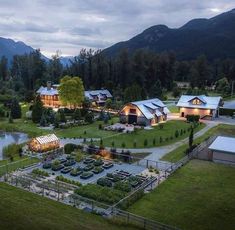 an aerial view of a farm with several buildings and gardens in the foreground, surrounded by mountains