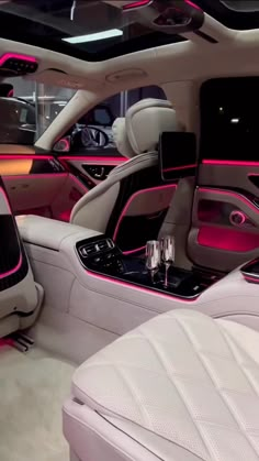 the interior of a luxury car with pink lighting