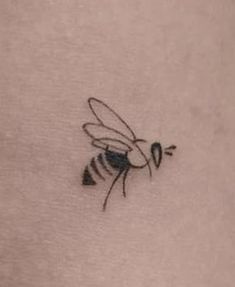 a small tattoo of a bee on the back of a woman's left arm