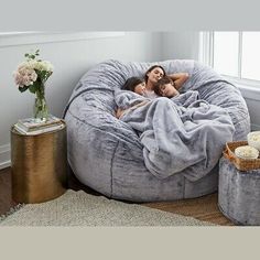 a woman laying in a large bean bag chair on top of a rug next to two small stools