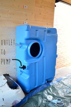 a large blue barrel sitting in the middle of a room next to a sign that says outlet to pump