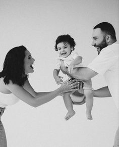 a man and woman holding a baby up in the air