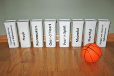 a basketball sitting next to five trash cans with labels on them and an orange ball in the middle