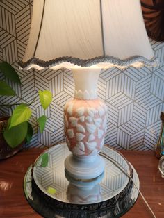 a lamp sitting on top of a table next to a glass plate with a flower design