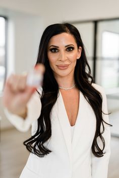 a woman in a white suit pointing at the camera