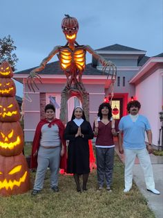 four people standing in front of a halloween decoration