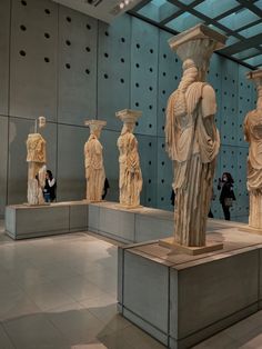 several statues in a room with people looking at them