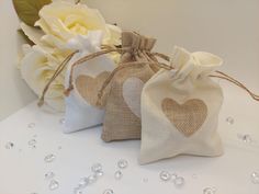 three bags with hearts on them are sitting next to some white flowers and pearls in the background