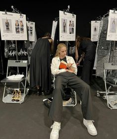 a woman sitting on a chair in front of some posters and other mannequins