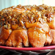 a bundt cake covered in caramel and pecans on a red platter