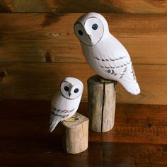 two white owl figurines sitting on top of a wooden post next to each other