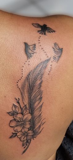 a woman's back with a bird and flower tattoo on it