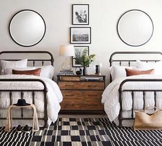 two beds in a room with pictures on the wall above them and a rug underneath them