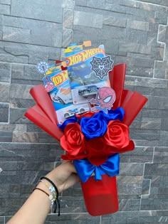 a person is holding a red, white and blue flower bouquet in front of a brick wall