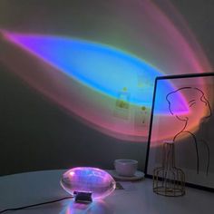 a table topped with a glass bowl filled with liquid next to a framed drawing on the wall