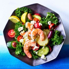 a salad with shrimp, tomatoes, cucumbers and feta cheese on it