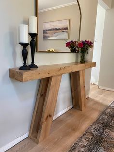 a wooden table with two vases on top of it and a mirror above it