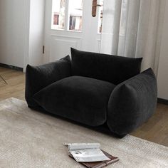 a black couch sitting on top of a wooden floor next to a white door and window