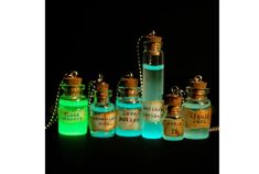 several small bottles with glow in the dark on top of a black surface, one has a key chain attached to it