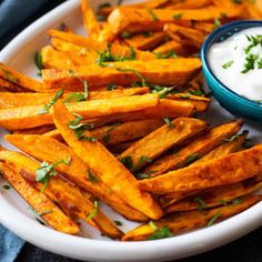 baked sweet potato wedges with ranch dressing on a white platter, ready to be eaten