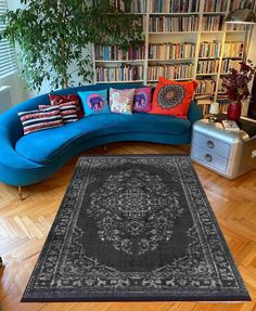 a blue couch sitting next to a large rug on top of a hard wood floor