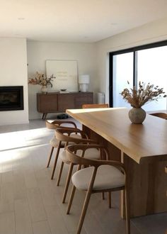 a dining room table with chairs and a potted plant on it in front of a fireplace